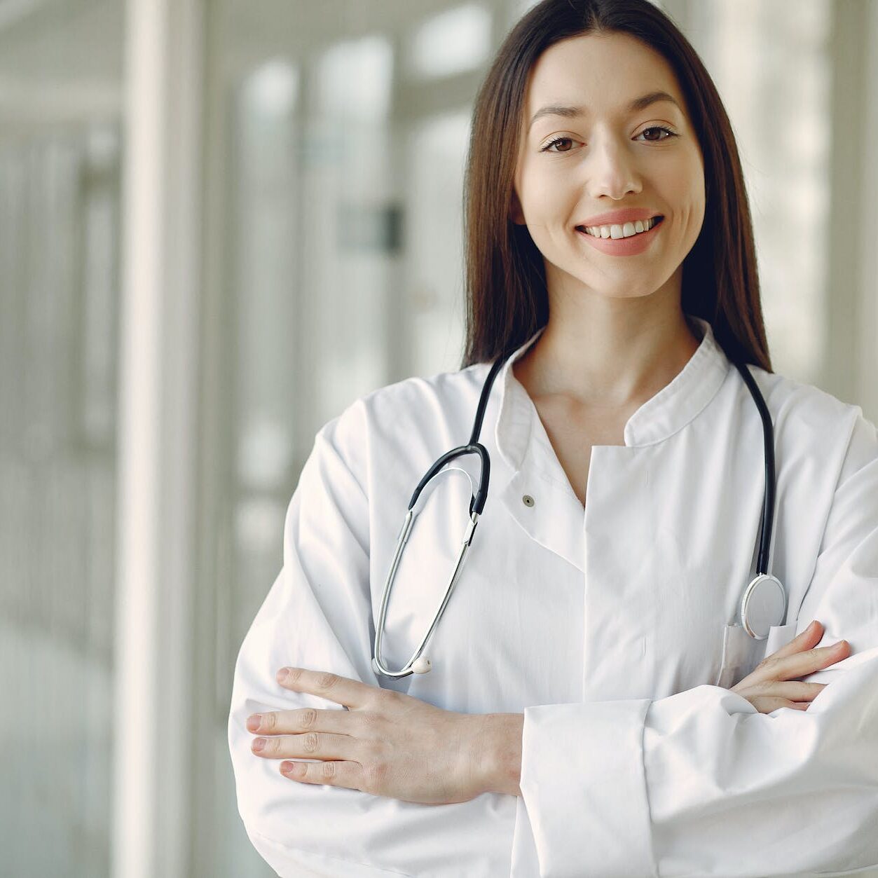 crop doctor in medical uniform with stethoscope standing in clinic corridor